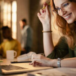 Happy businesswoman working late on a computer in the office.
