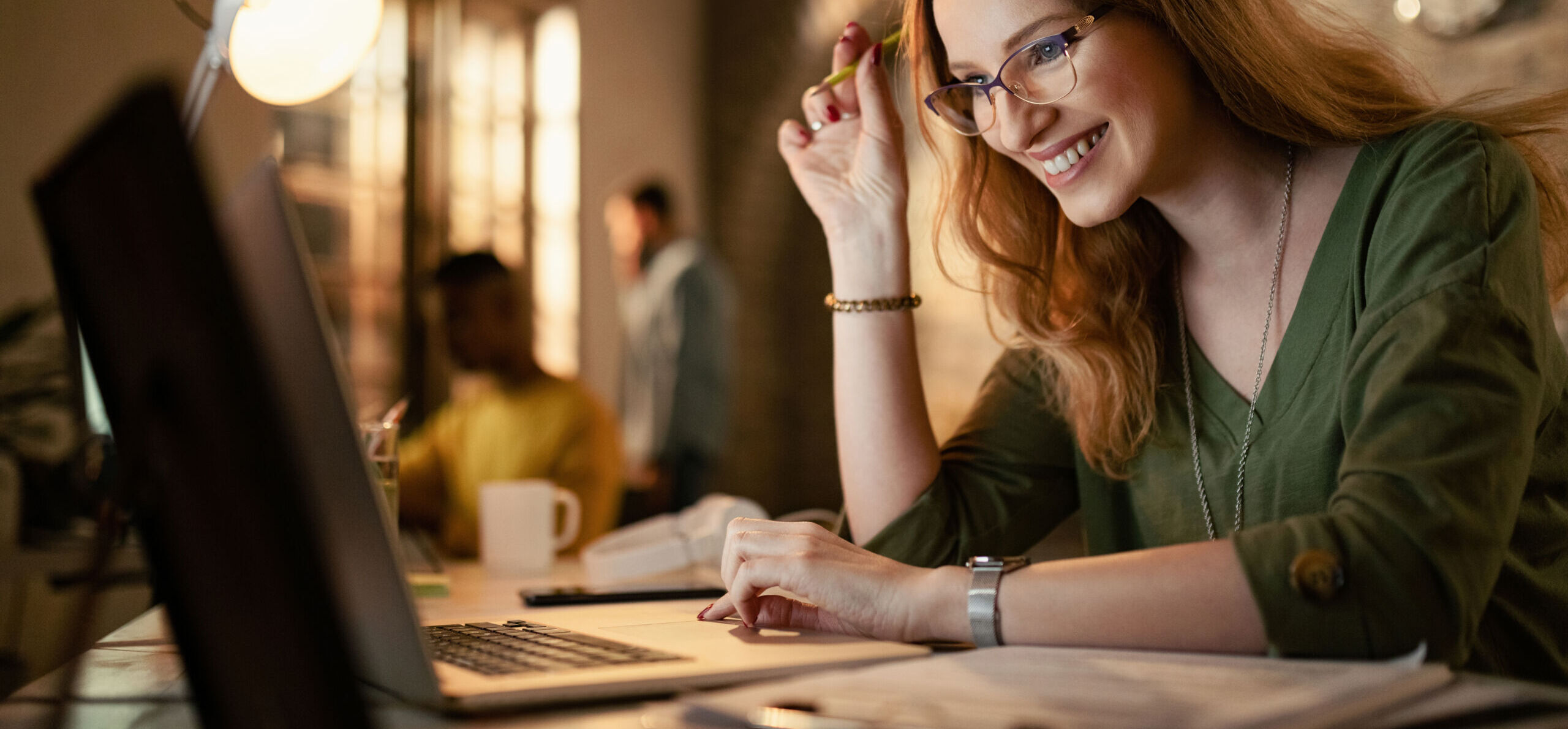 Happy businesswoman working late on a computer in the office.